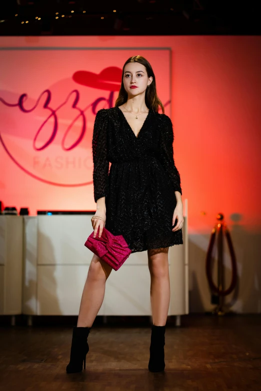 woman in black dress holding a pink purse at fashion show