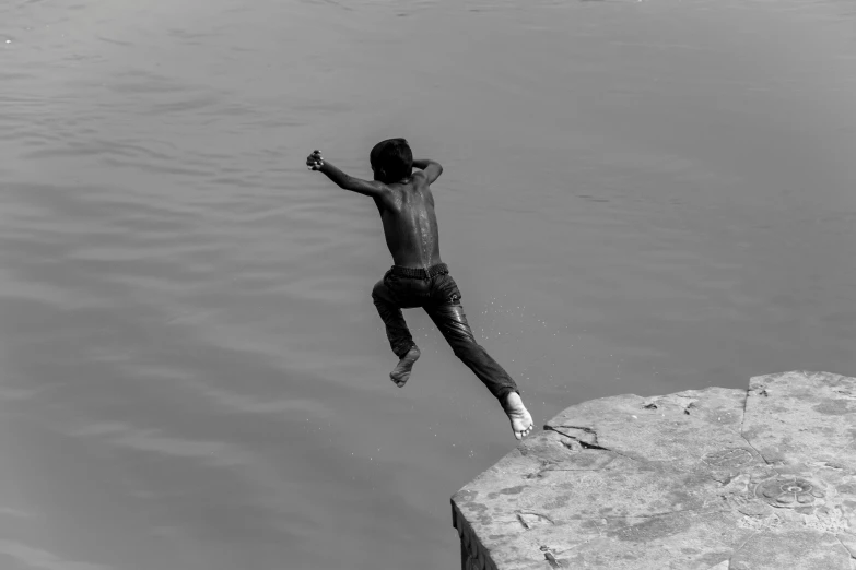 a man jumping into a body of water from a stone cliff