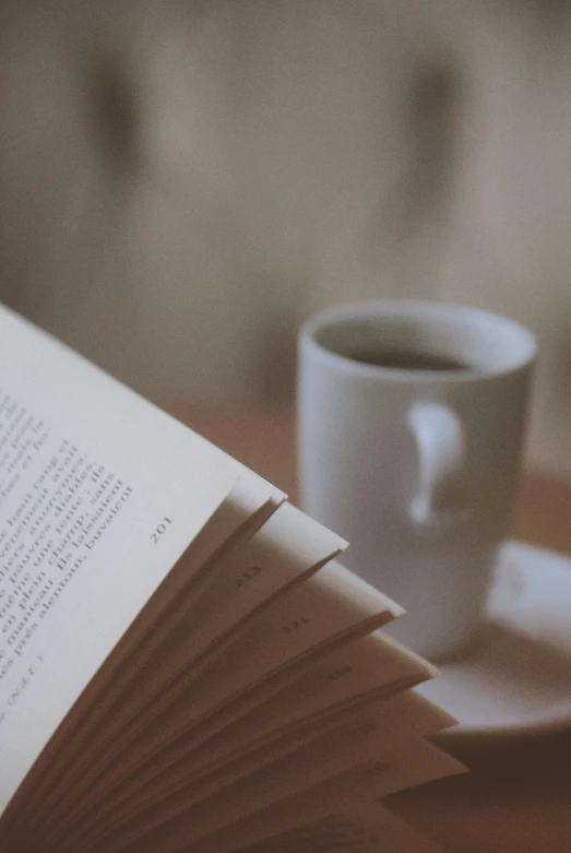 the opened book sits next to a coffee cup