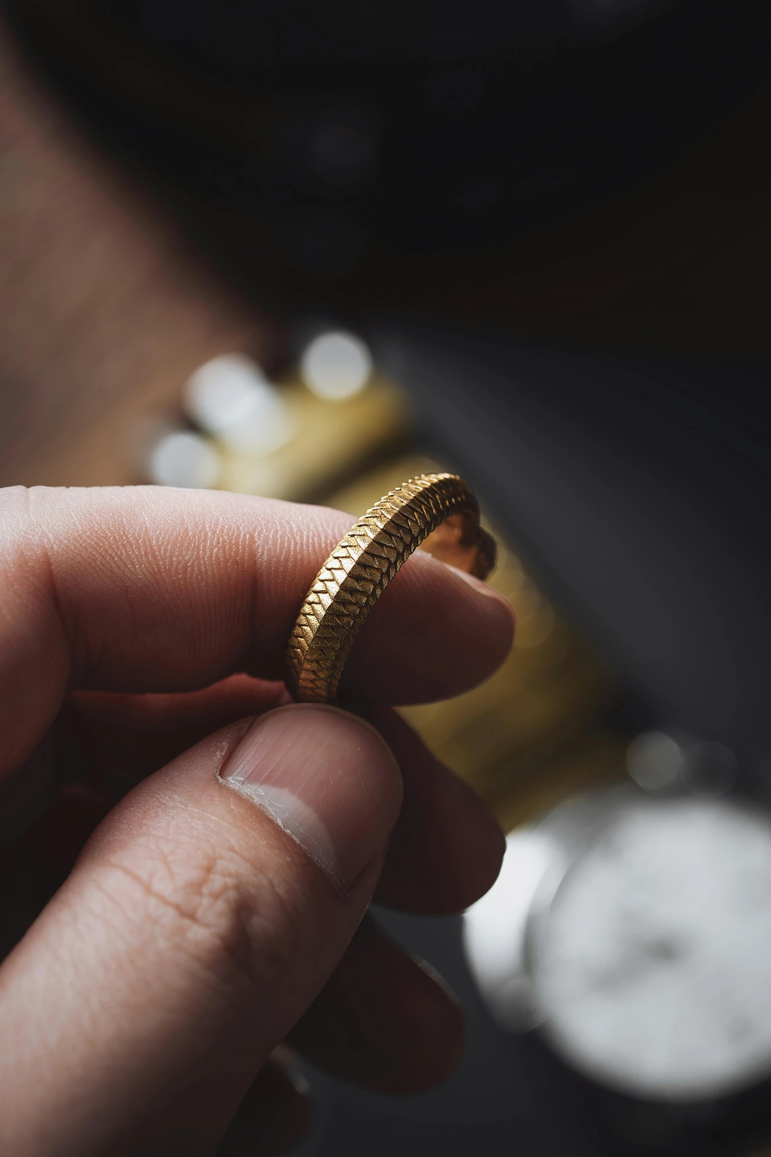 someone holds up their gold ring that has been inscribed in