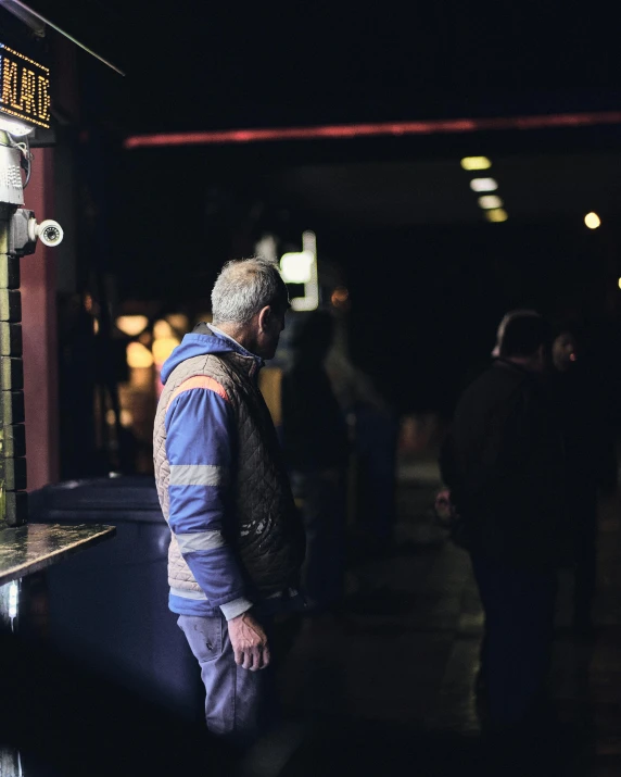 an older man standing outside a bar in the dark