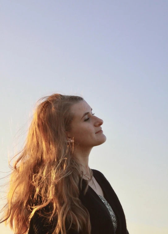 a young woman smiles and looks at the sky