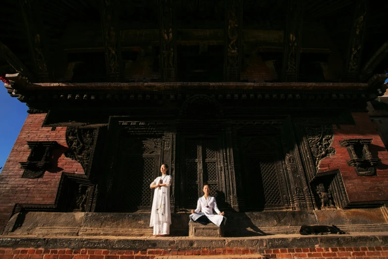 two people sitting on the side of a tall building