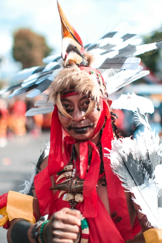 a man in feathers on his head, headgear and face paint