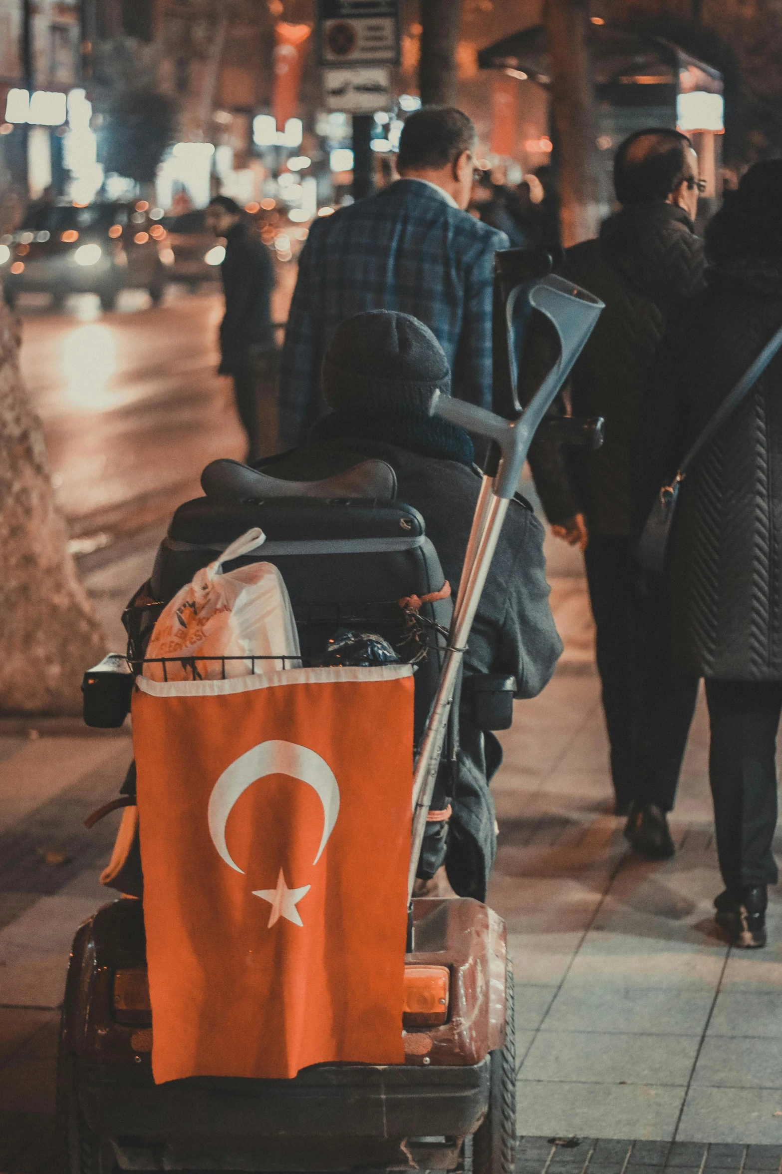 a man hing a cart down the street carrying a red flag