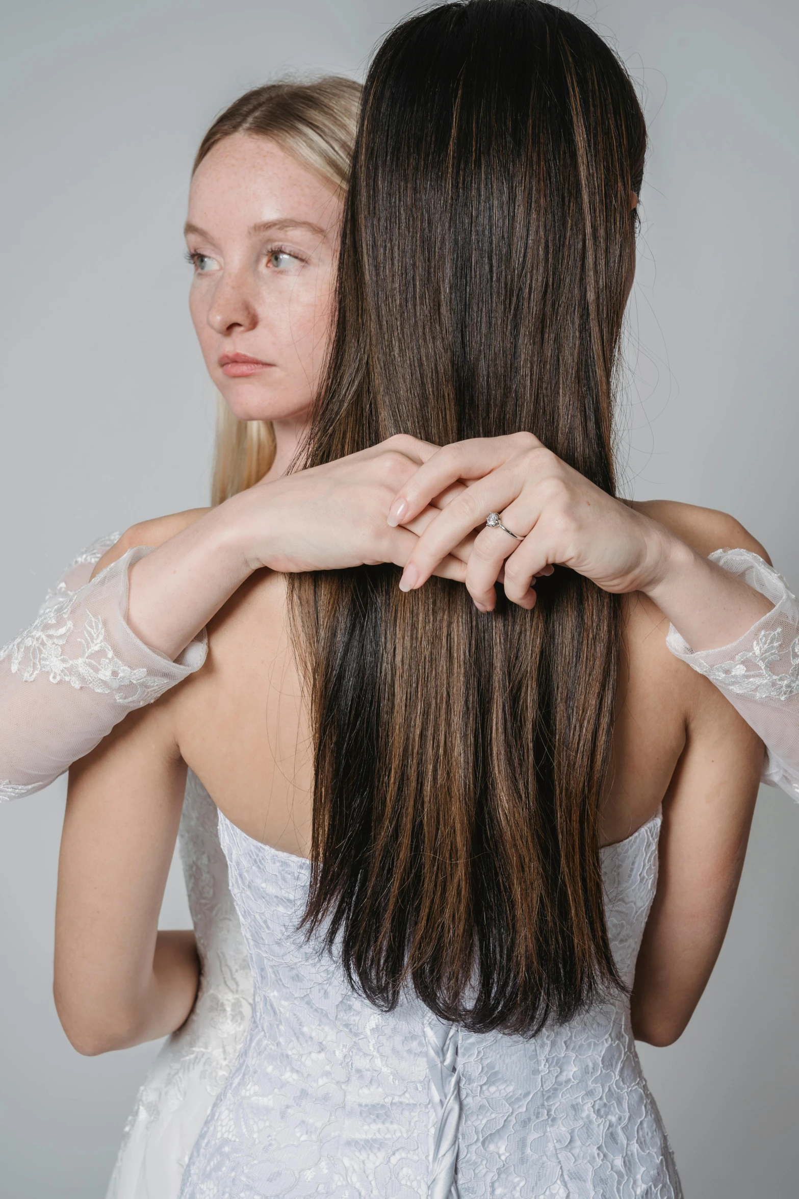 two woman in lace wedding dress touching each other's shoulders