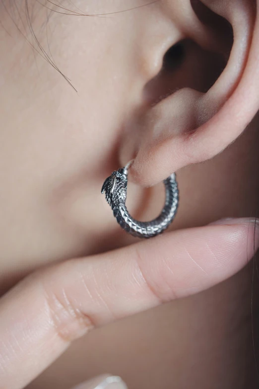 closeup of a person's ear and a circular silver object