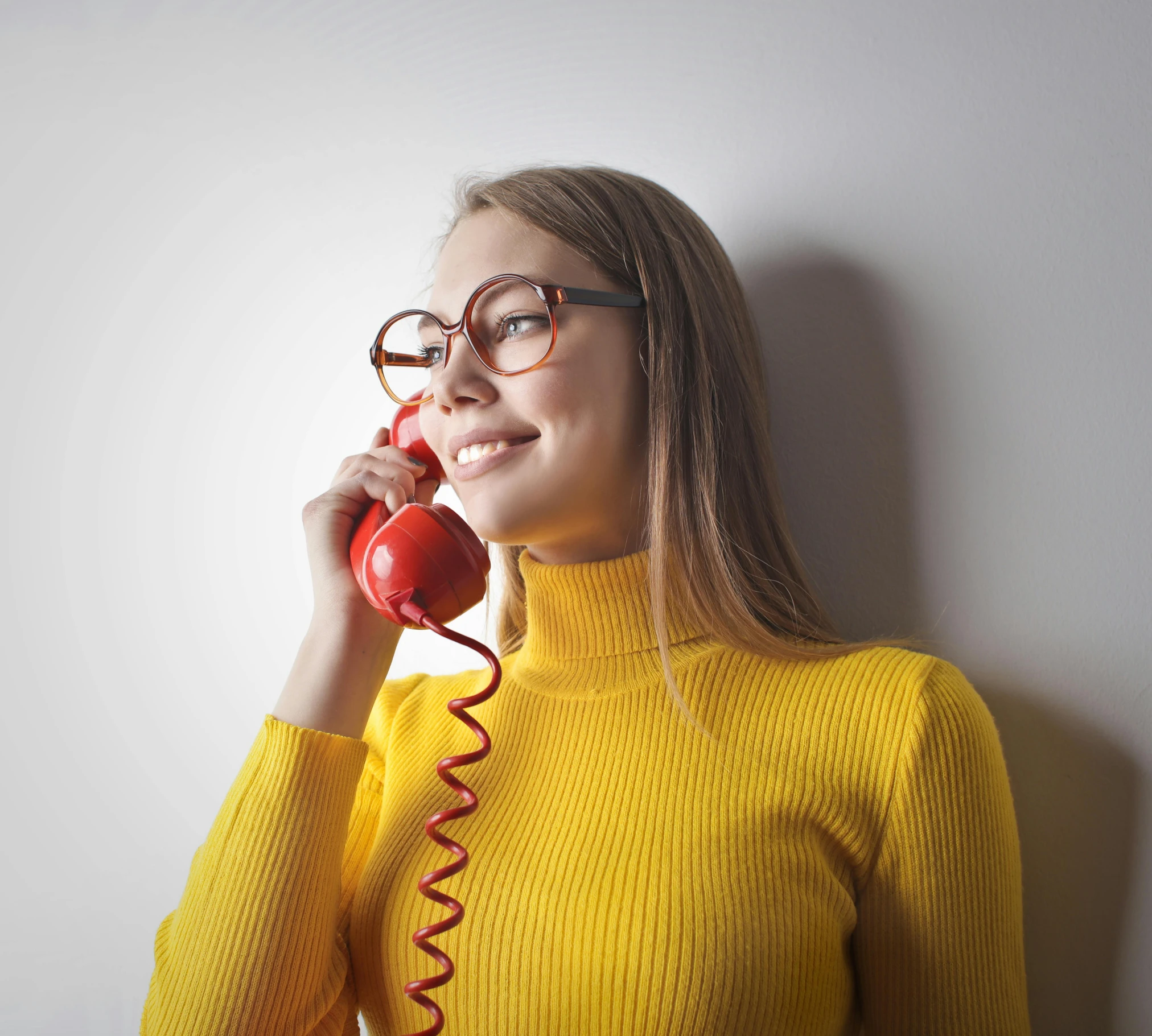 a young woman holding a red phone up to her face