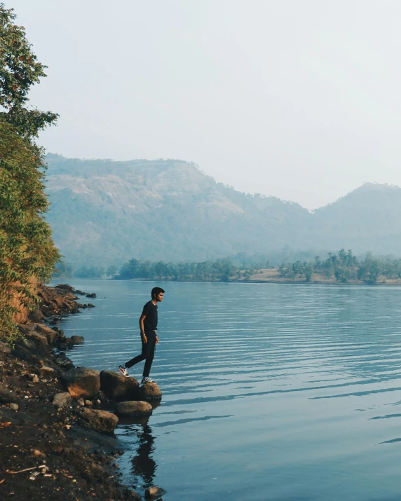 a man stands on a rock in the middle of a lake