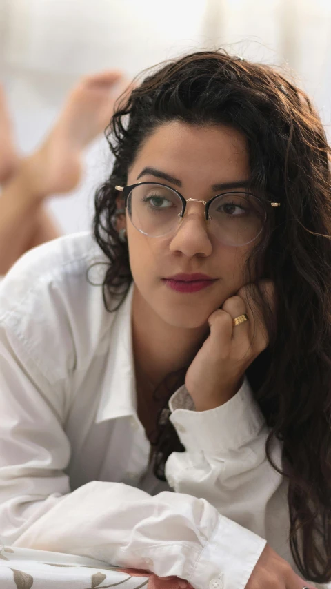 a young woman wearing glasses sits at a desk