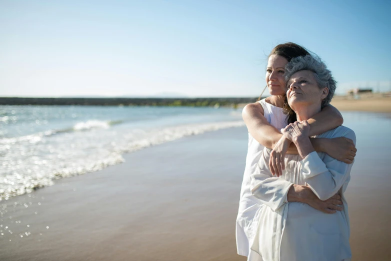 two women emce while standing on a beach