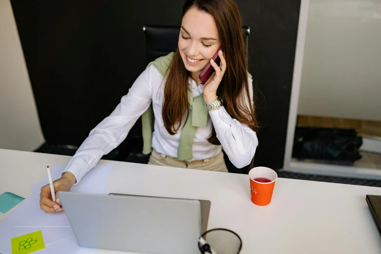 a woman is talking on the telephone at her desk