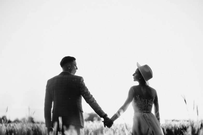 black and white pograph of couple holding hands, in field