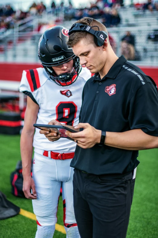 a football player wearing a helmet and using his cell phone