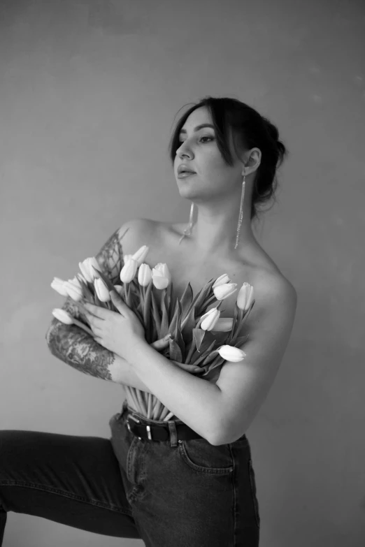 an elegant woman in jeans and heels holds a bouquet of tulips