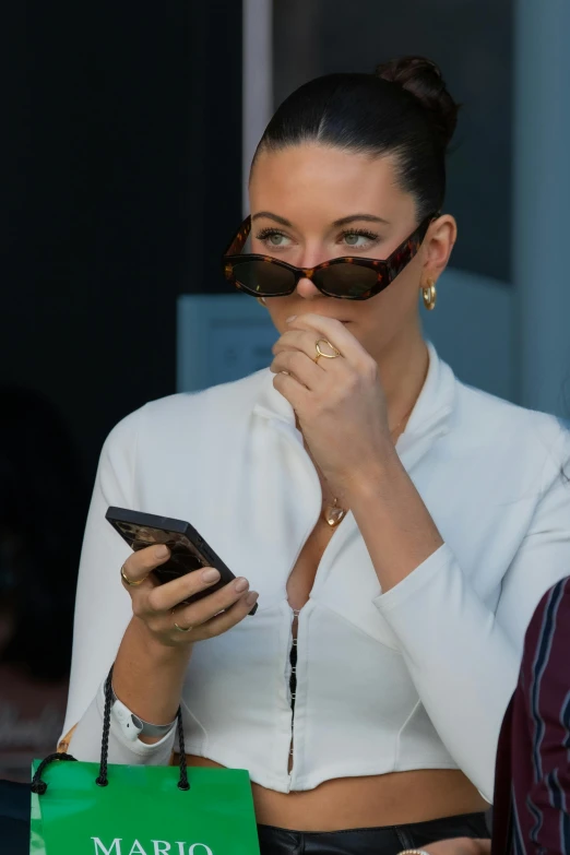 a woman with glasses holds her face while looking at a cellphone