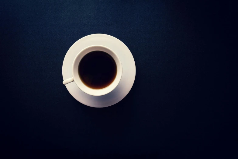 an overhead view of a cup of coffee on a black table