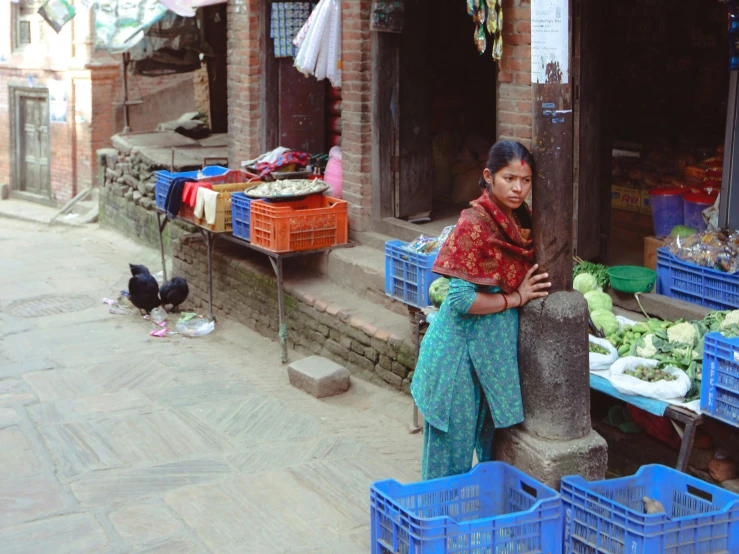 a woman sitting outside with several crates of fruits and vegetables