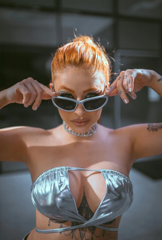 a lady with red hair wearing shiny clothes and sunglasses