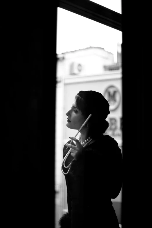 woman standing by window while holding a cellphone up to her ear