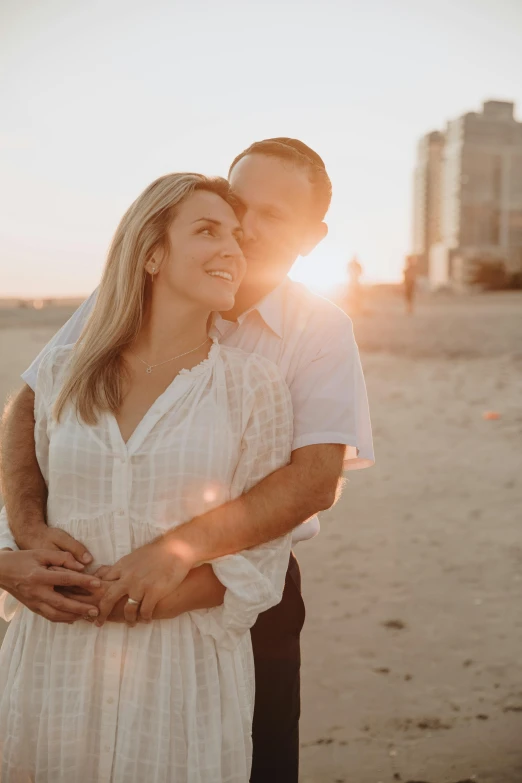 couple emce on the beach at sunset in front of a skyscr