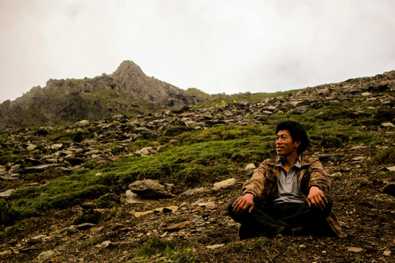 a man sitting on a rock covered hill