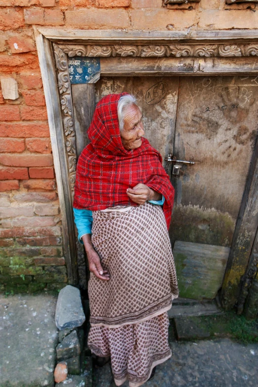 woman in red shawl standing near brick building