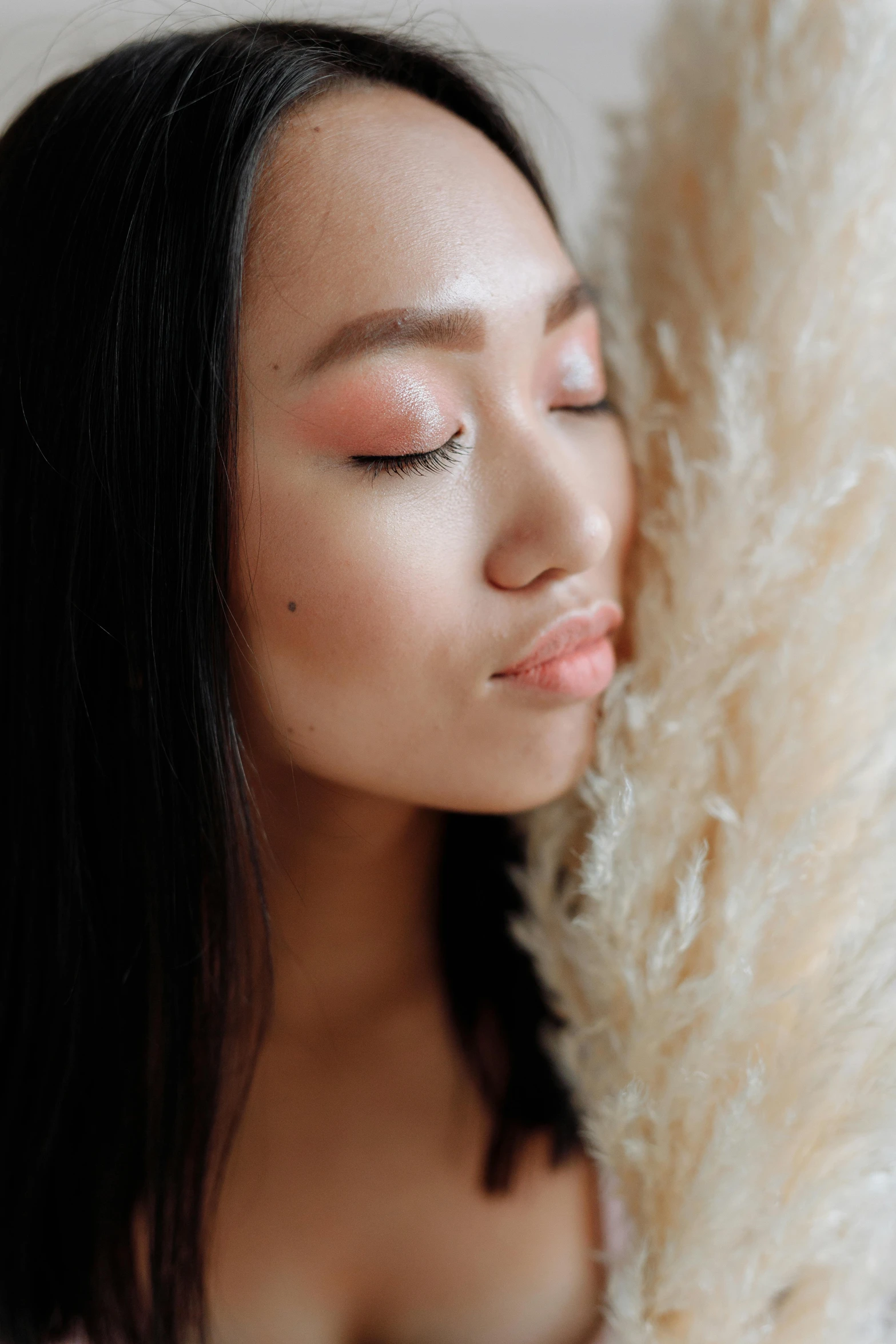 woman with makeup on her eyes holding a furry animal fur