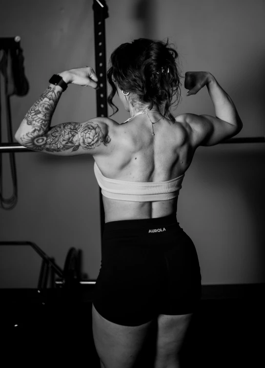a woman with tattoos lifting a bar