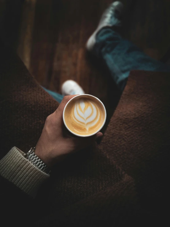 a person holding a cup of cappuccino in their hand