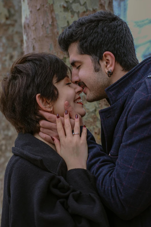 a man and a woman standing together by some trees