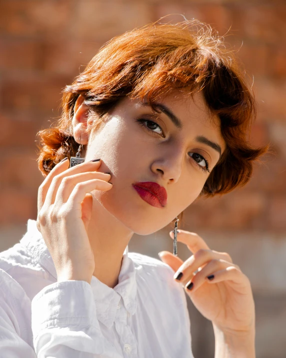 a woman with red hair holds her hand to her ear