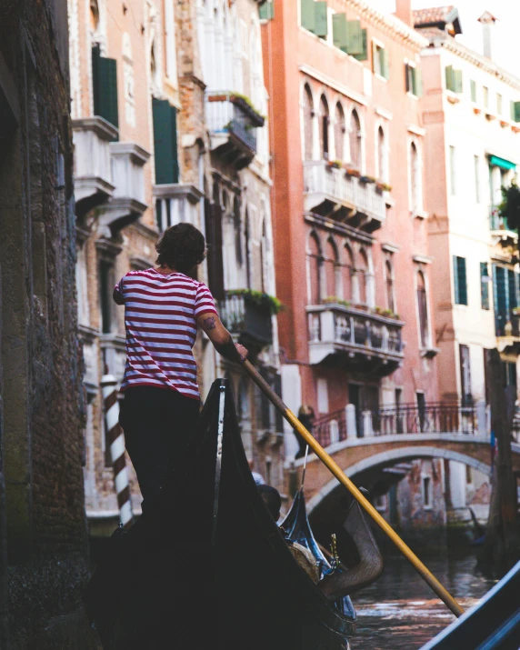 a man is riding on a boat that goes down the canal