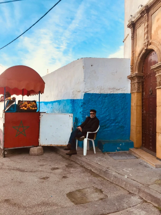 a man is sitting on a chair in front of a food vendor