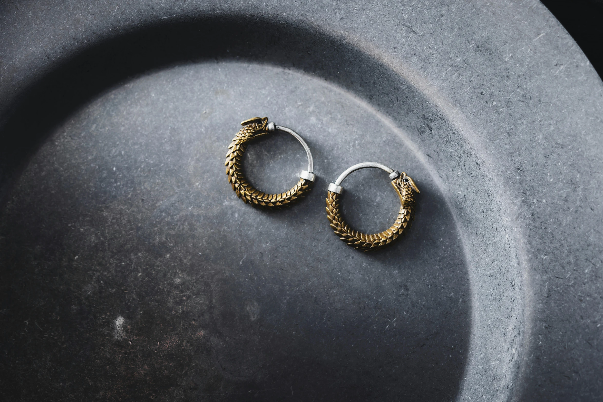 gold earrings on top of a plate on grey tablecloth