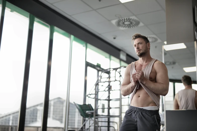 a shirtless man with a tie standing by the wall