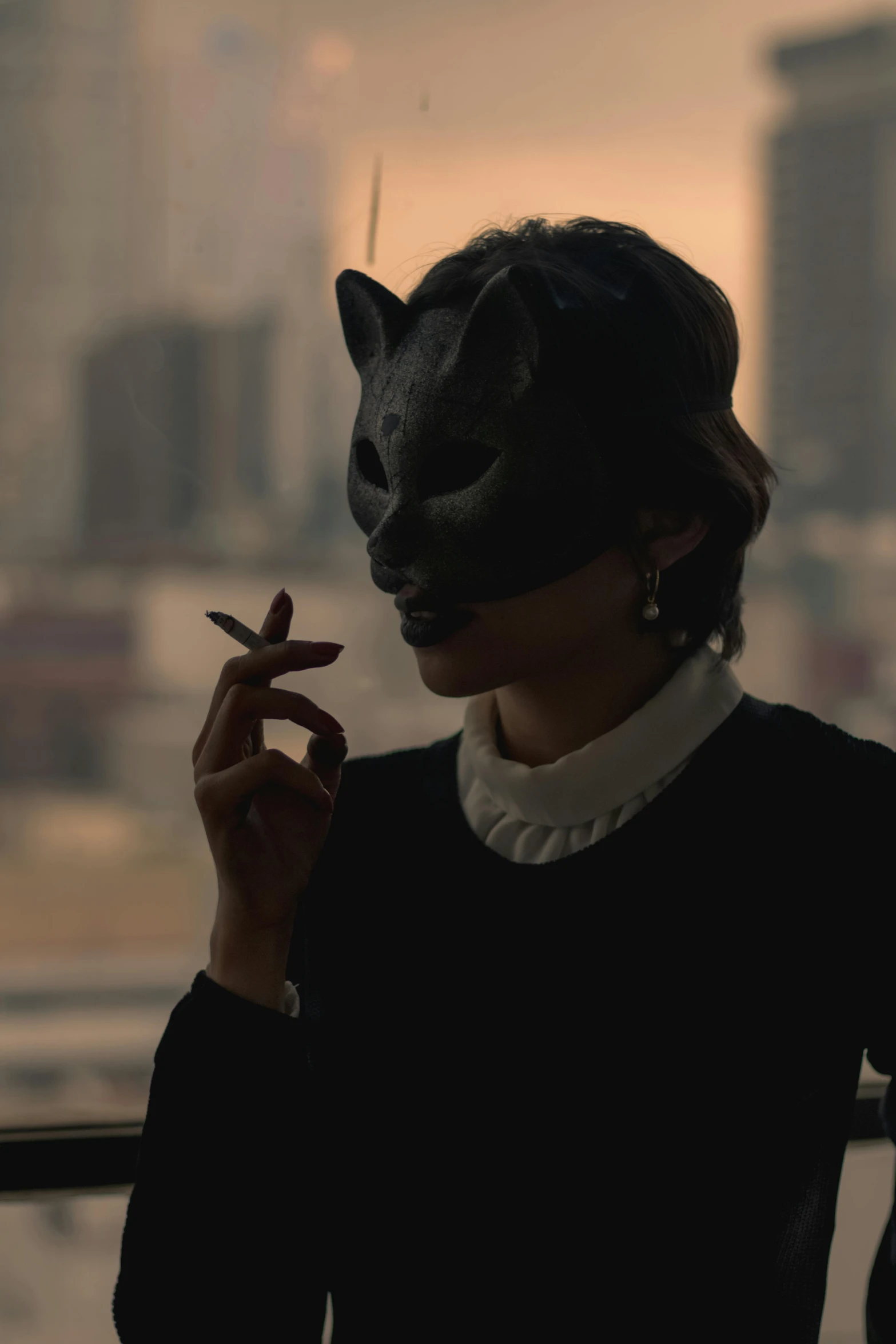 woman with a black cat mask holding a cigarette