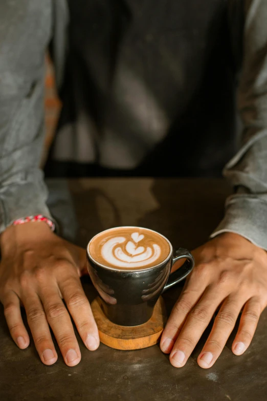 a person with their hands on top of a cup of coffee