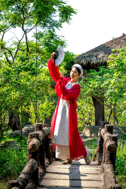 woman in traditional attire crossing a wooden bridge over water