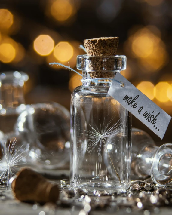 a small bottle of tiny dandelions sits next to wineglasses on the table