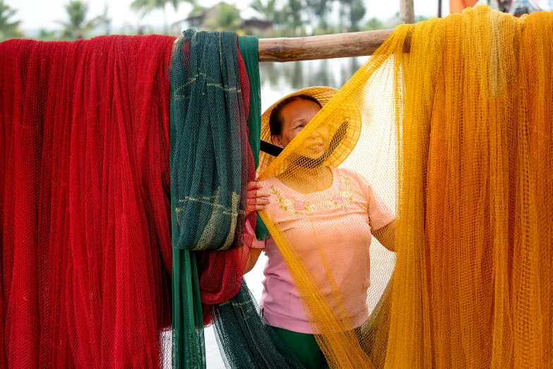 an asian woman looking through some colorful ropes