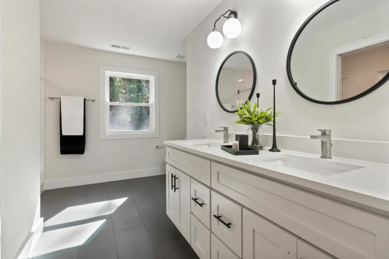 this bathroom has a double vanity and round mirrors