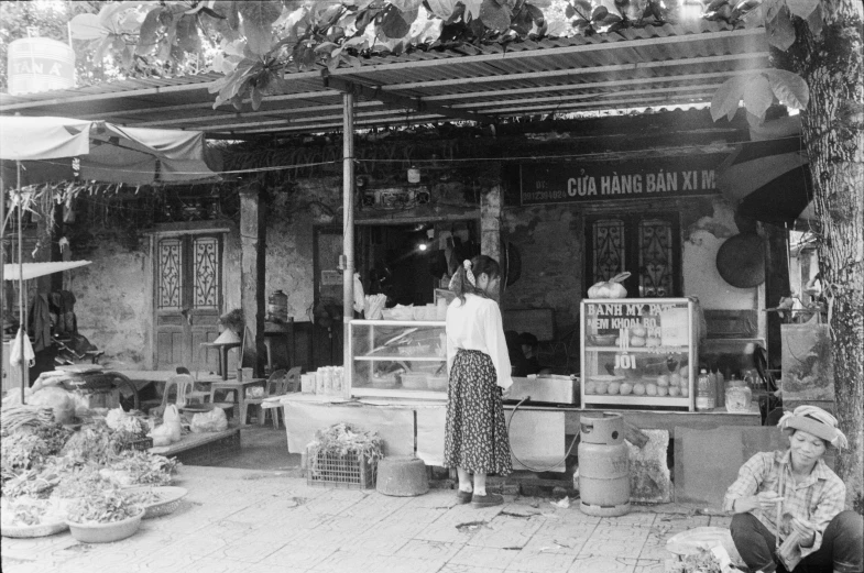 an old po of women standing at a produce stand