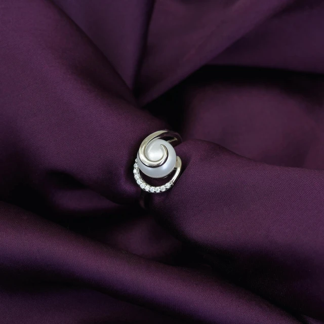 a ring on top of purple cloth next to a piece of clothing