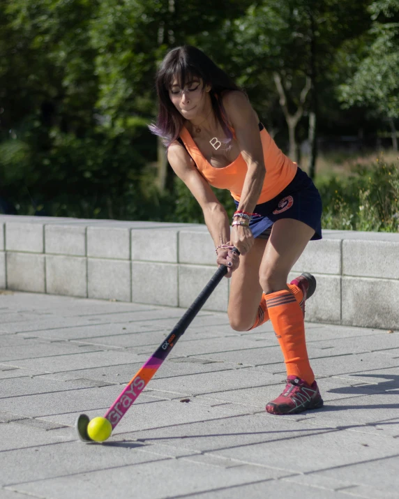 a girl in an orange shirt playing croquet ball