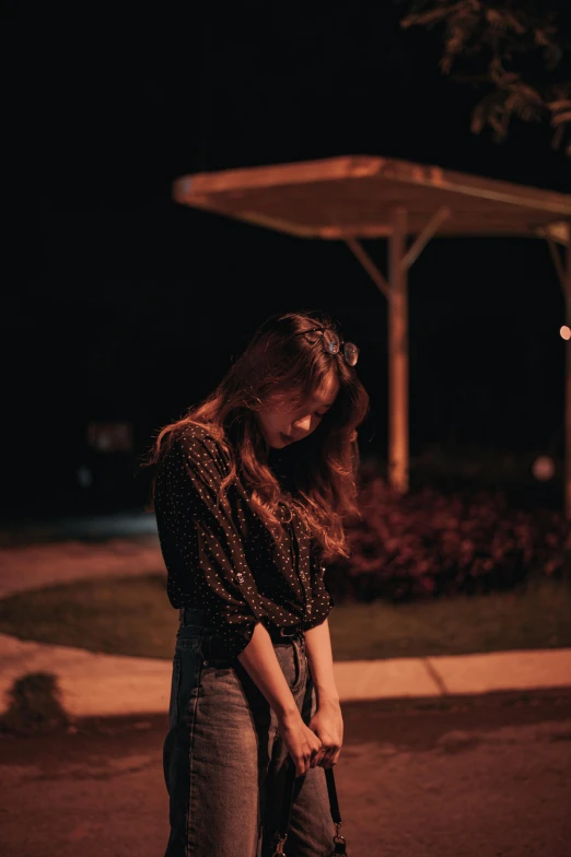 a woman is standing by the street at night holding her hand in her pocket