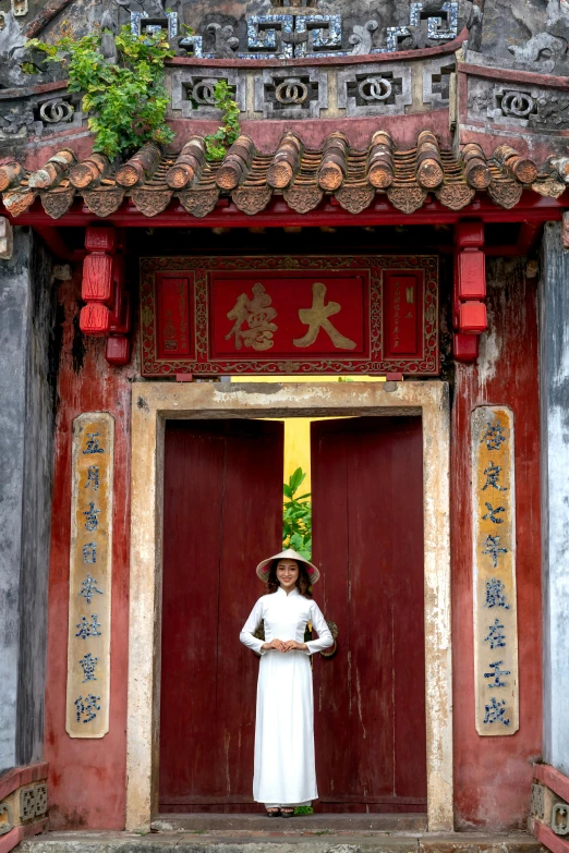 the man stands next to a very ornate chinese doorway