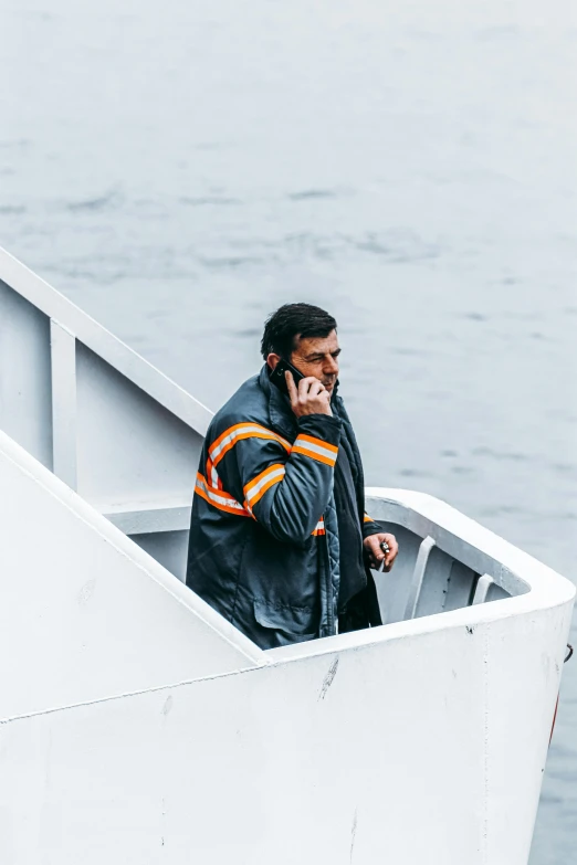 the man is talking on his cell phone while sitting in the boat