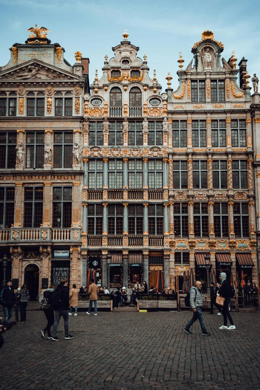 a group of people walking down the street with many windows on the building