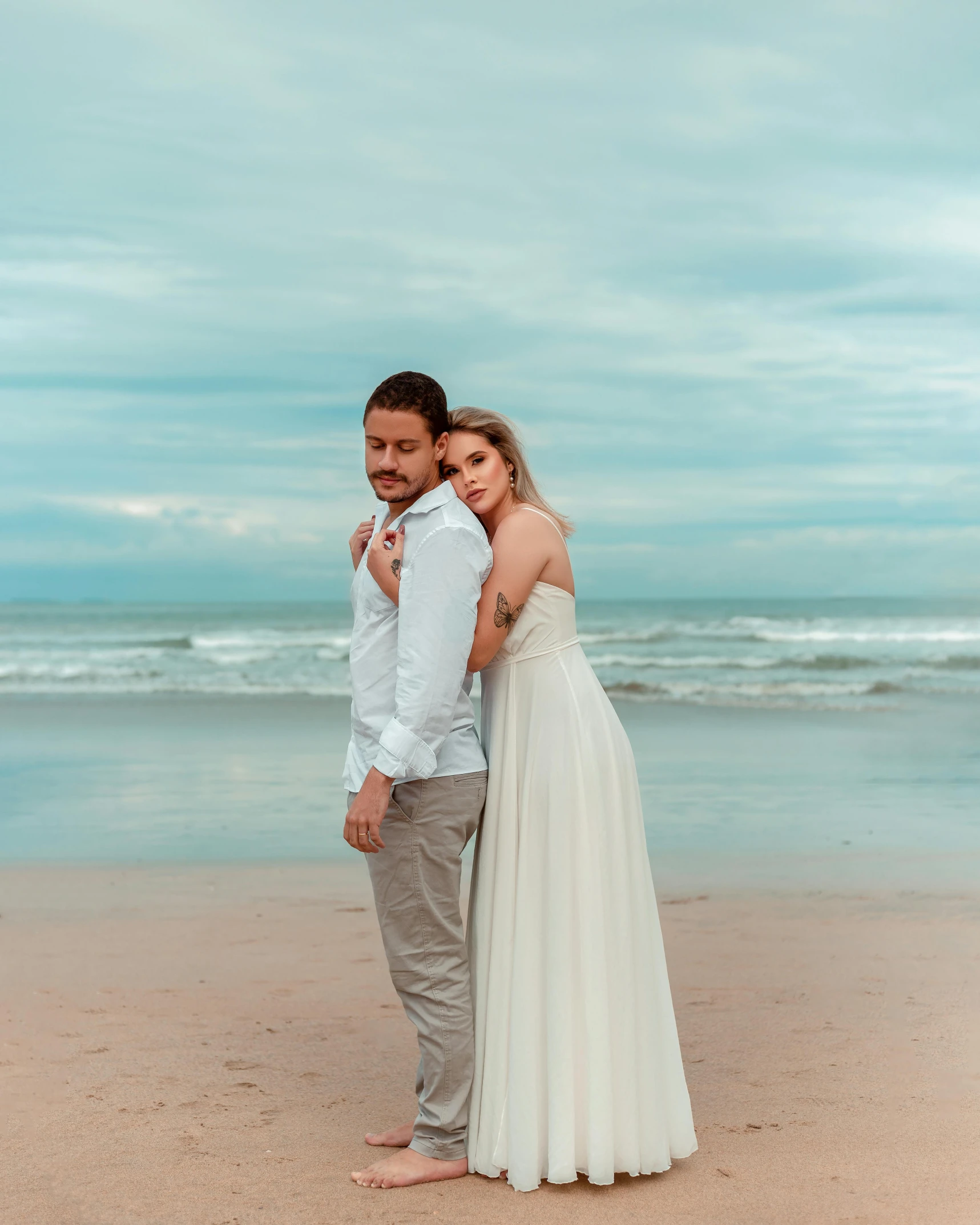 man and woman on the beach posing for a po